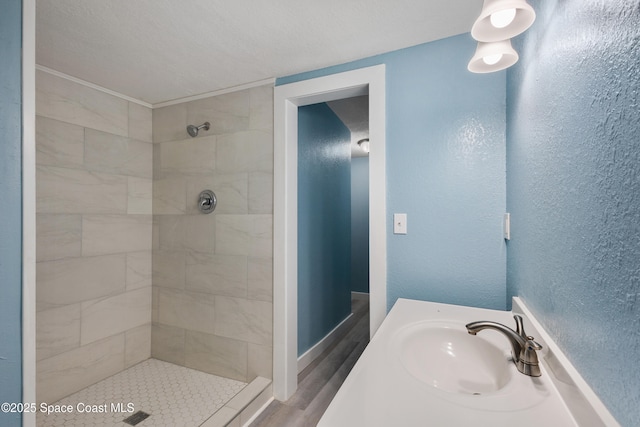 bathroom featuring wood-type flooring, a tile shower, and sink