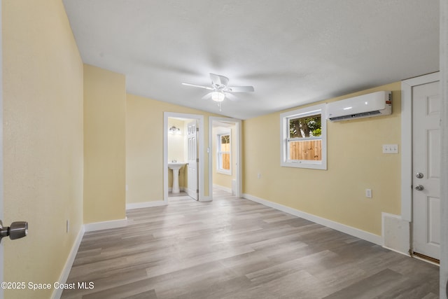 spare room with a wall mounted AC, ceiling fan, light hardwood / wood-style flooring, and lofted ceiling