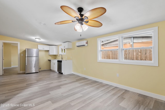 kitchen featuring white cabinetry, sink, stainless steel appliances, a wall mounted air conditioner, and light wood-type flooring