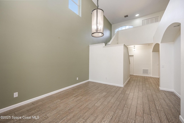 unfurnished living room featuring hardwood / wood-style floors and a towering ceiling