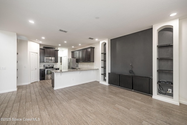 kitchen featuring built in features, kitchen peninsula, and appliances with stainless steel finishes