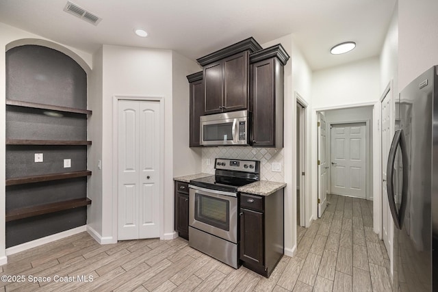 kitchen featuring light stone countertops, appliances with stainless steel finishes, backsplash, and dark brown cabinets