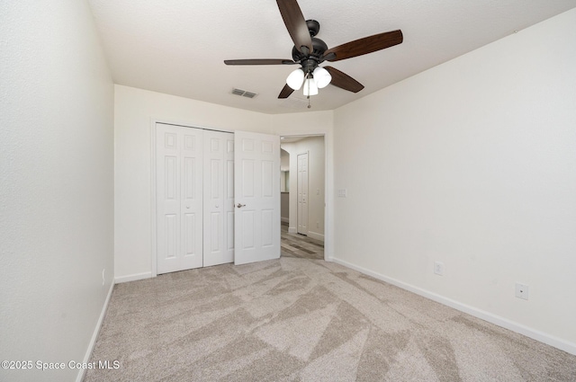 unfurnished bedroom featuring light carpet, a closet, and ceiling fan