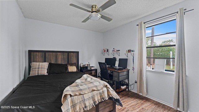 bedroom featuring hardwood / wood-style floors, ceiling fan, a textured ceiling, and multiple windows