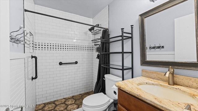 bathroom featuring a tile shower, vanity, and toilet