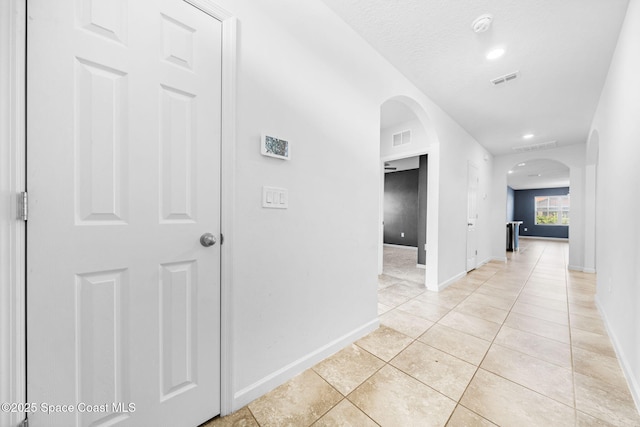 hallway with light tile patterned floors and a textured ceiling