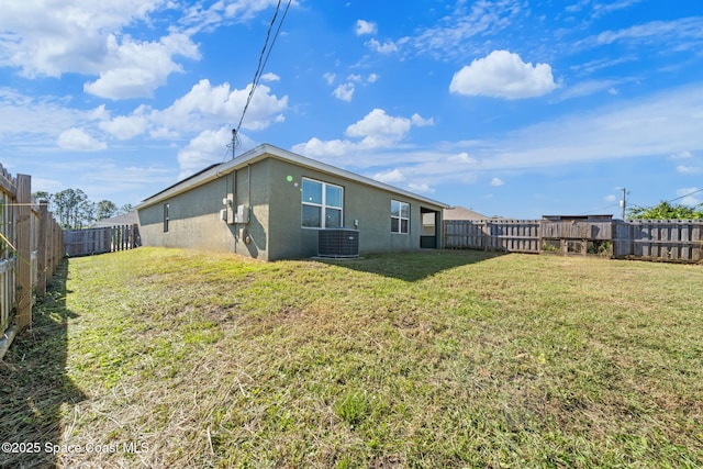 rear view of property featuring a lawn and central AC unit