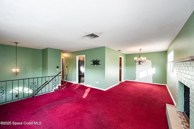 unfurnished living room with a fireplace, an inviting chandelier, a textured ceiling, and carpet floors