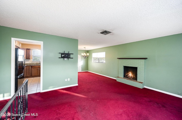 carpeted living room with a textured ceiling, a brick fireplace, and a chandelier