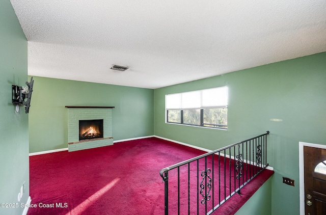 unfurnished living room featuring a textured ceiling, carpet, and a fireplace