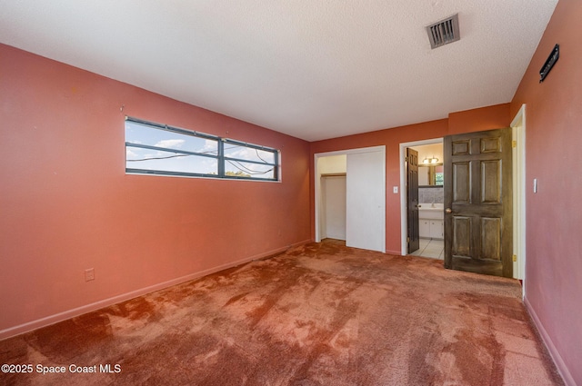 unfurnished bedroom featuring a closet, ensuite bath, and carpet