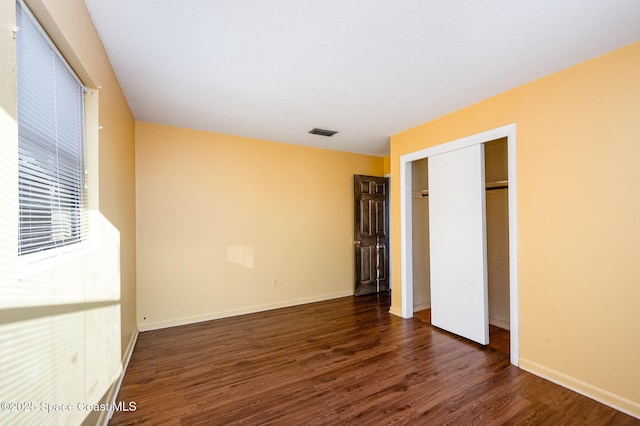 unfurnished bedroom featuring a closet and dark wood-type flooring