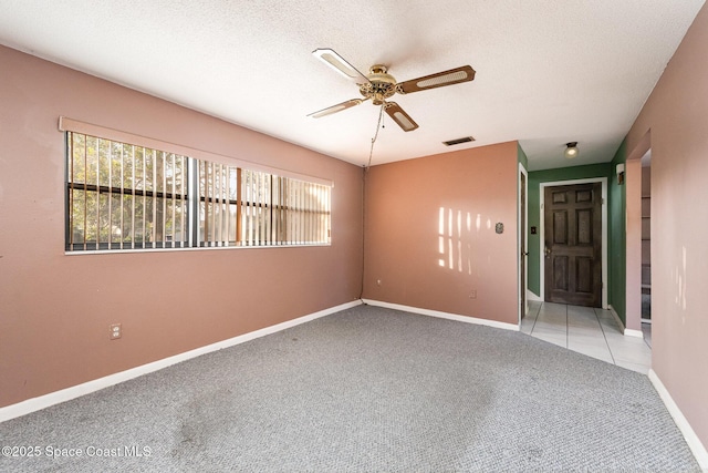 unfurnished room with light colored carpet, ceiling fan, and a textured ceiling