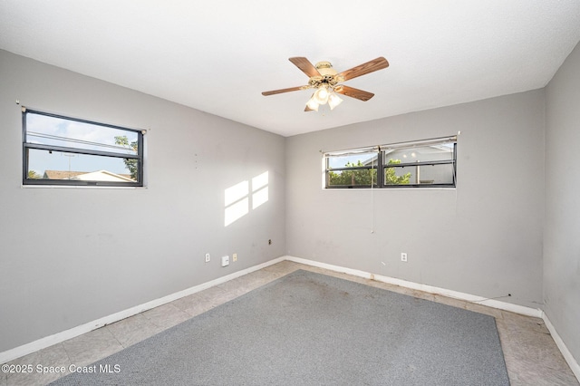 empty room with ceiling fan and light tile patterned flooring