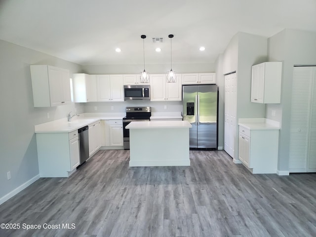 kitchen featuring hanging light fixtures, appliances with stainless steel finishes, sink, white cabinetry, and a kitchen island