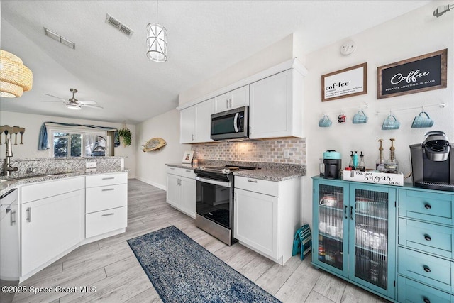 kitchen featuring pendant lighting, ceiling fan, white cabinetry, and appliances with stainless steel finishes