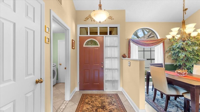 entrance foyer with a notable chandelier, light tile patterned flooring, washer / dryer, and a textured ceiling