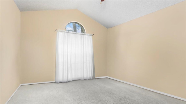 carpeted empty room with a textured ceiling and vaulted ceiling