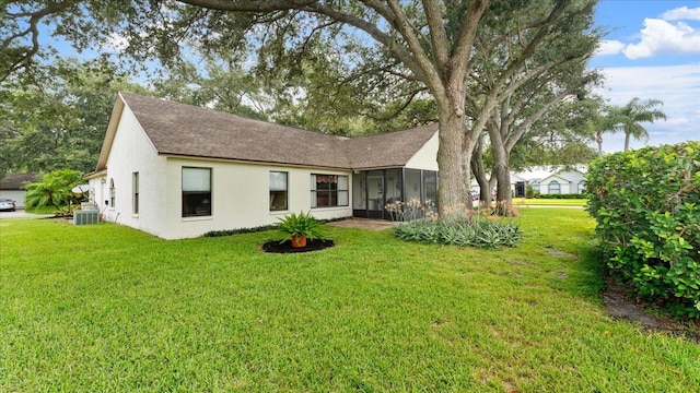 rear view of house with a lawn, central air condition unit, and a sunroom