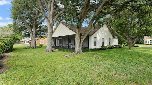 rear view of property featuring a lawn and a sunroom