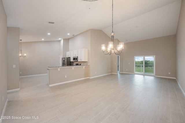 interior space featuring white cabinetry, stainless steel appliances, pendant lighting, a kitchen bar, and light wood-type flooring