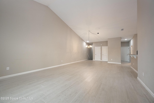 empty room featuring vaulted ceiling, light hardwood / wood-style flooring, and a notable chandelier