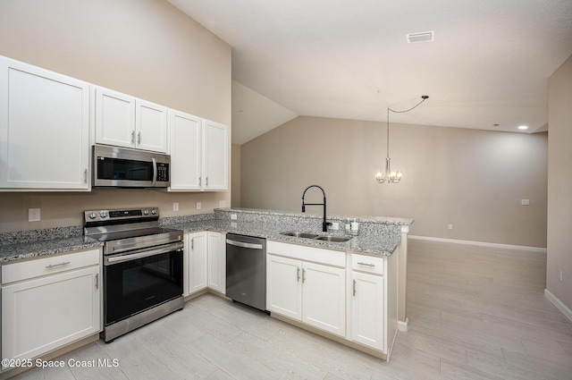 kitchen featuring kitchen peninsula, sink, decorative light fixtures, and appliances with stainless steel finishes