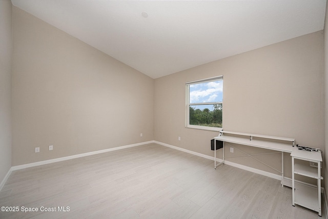 empty room with light hardwood / wood-style floors and vaulted ceiling