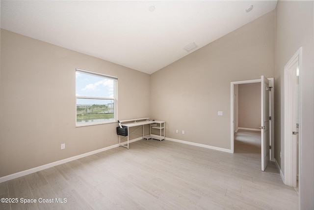 unfurnished room with light wood-type flooring and lofted ceiling