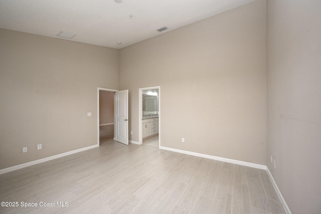 unfurnished room featuring light hardwood / wood-style floors and a high ceiling