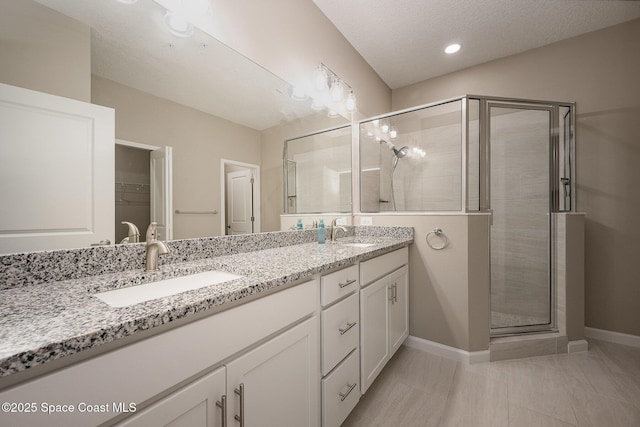 bathroom with vanity, a textured ceiling, and a shower with shower door