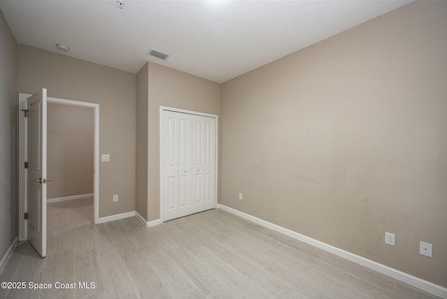 unfurnished bedroom featuring a textured ceiling, light hardwood / wood-style flooring, and a closet