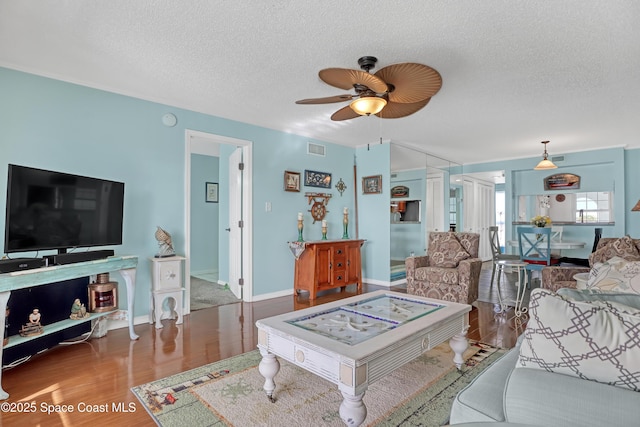 living room featuring hardwood / wood-style flooring, ceiling fan, and a textured ceiling