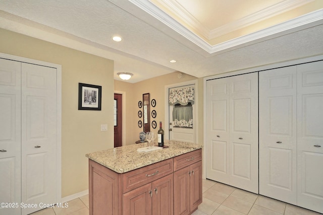 kitchen with a center island, light tile patterned flooring, light stone countertops, and ornamental molding