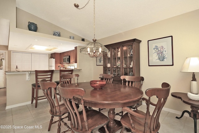 tiled dining area with lofted ceiling and a chandelier