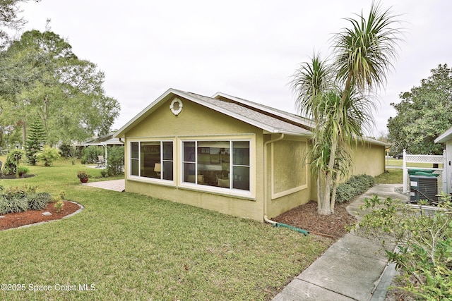 view of side of home with a lawn and central AC