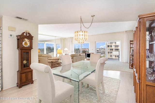 dining space with a chandelier, visible vents, and light wood-style floors