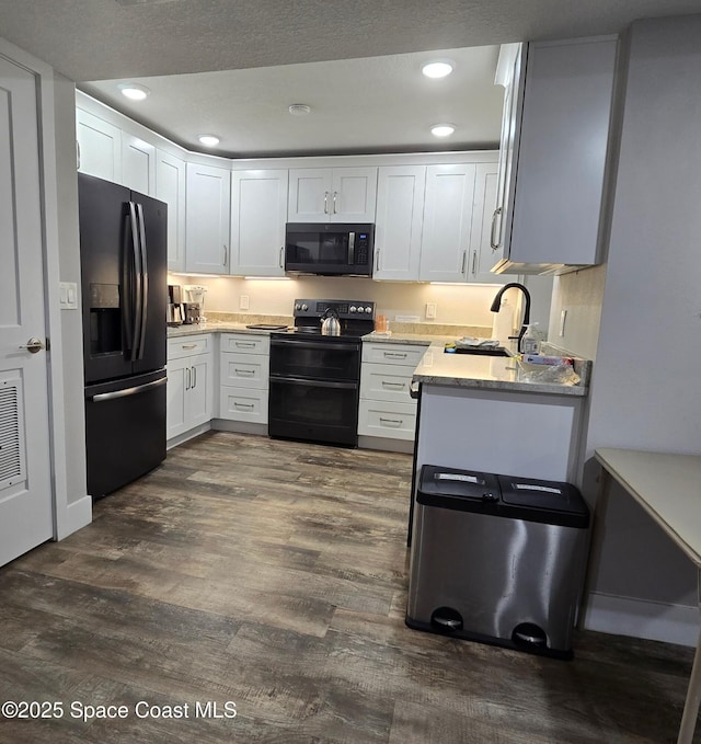 kitchen with white cabinets, dark wood-style flooring, black appliances, a sink, and recessed lighting