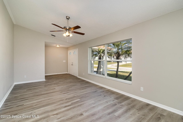 spare room featuring ceiling fan, light wood-type flooring, a textured ceiling, and vaulted ceiling