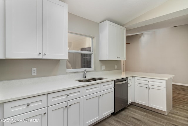 kitchen featuring sink, stainless steel dishwasher, kitchen peninsula, vaulted ceiling, and white cabinets