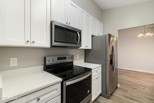 kitchen with an inviting chandelier, white cabinets, light hardwood / wood-style floors, and appliances with stainless steel finishes