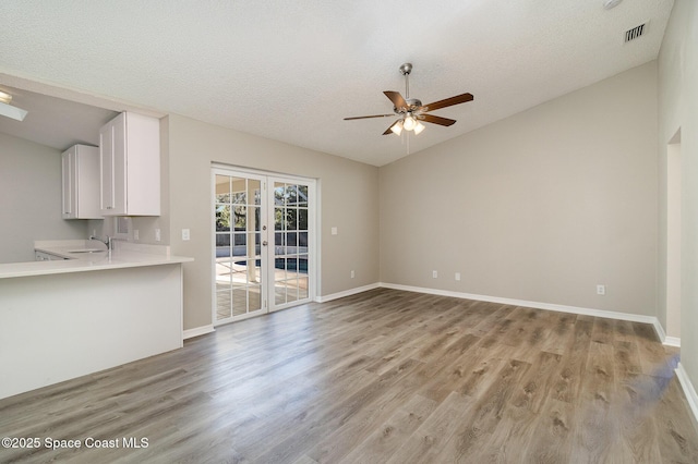 unfurnished living room with ceiling fan, french doors, sink, a textured ceiling, and light wood-type flooring