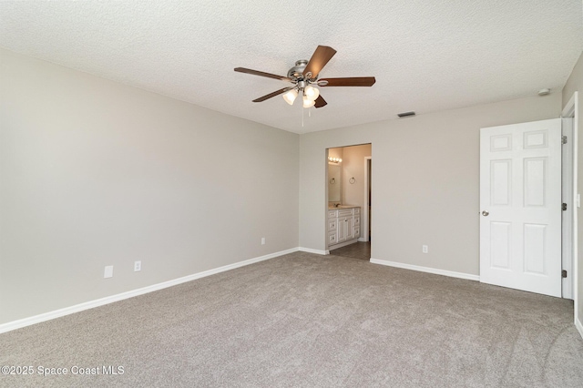 unfurnished bedroom featuring ensuite bathroom, ceiling fan, carpet floors, and a textured ceiling