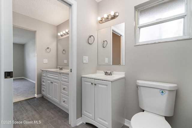 bathroom featuring vanity, toilet, and a textured ceiling