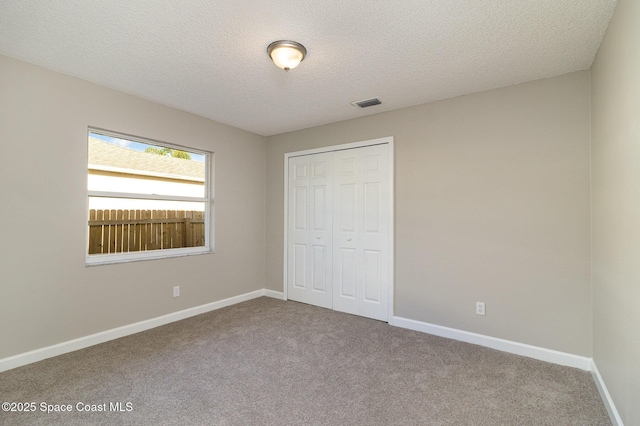 unfurnished bedroom with a textured ceiling, carpet floors, and a closet