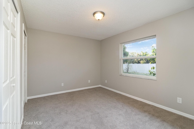 spare room with a textured ceiling and light colored carpet