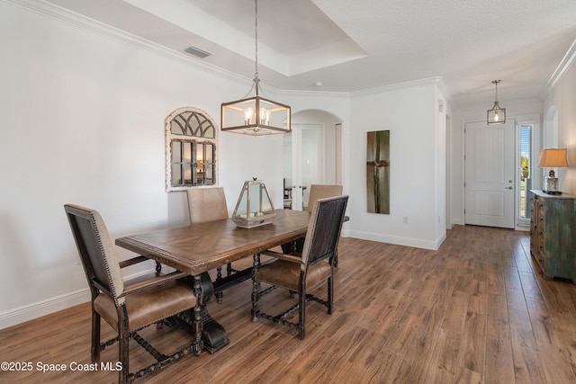 dining room with hardwood / wood-style floors, a chandelier, ornamental molding, and a tray ceiling