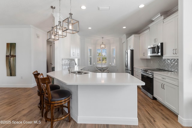 kitchen with appliances with stainless steel finishes, sink, decorative light fixtures, light hardwood / wood-style flooring, and white cabinets