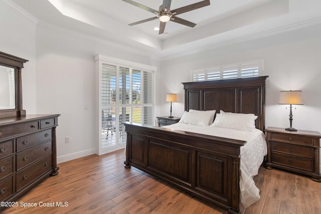 bedroom with ceiling fan, dark wood-type flooring, access to outside, and a tray ceiling