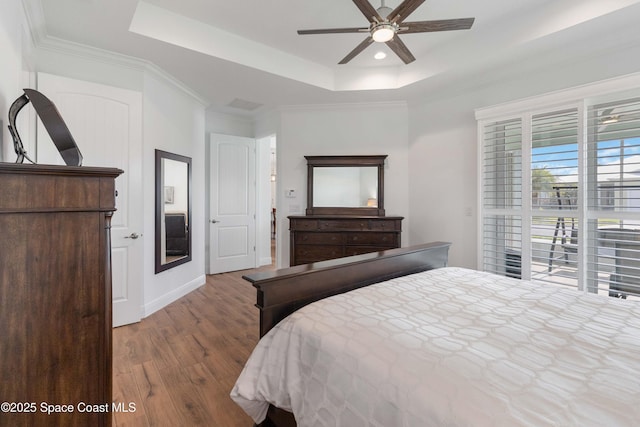 bedroom featuring ceiling fan, a raised ceiling, and wood-type flooring